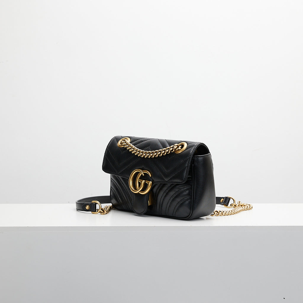 Black quilted handbag with gold chain \on a white background