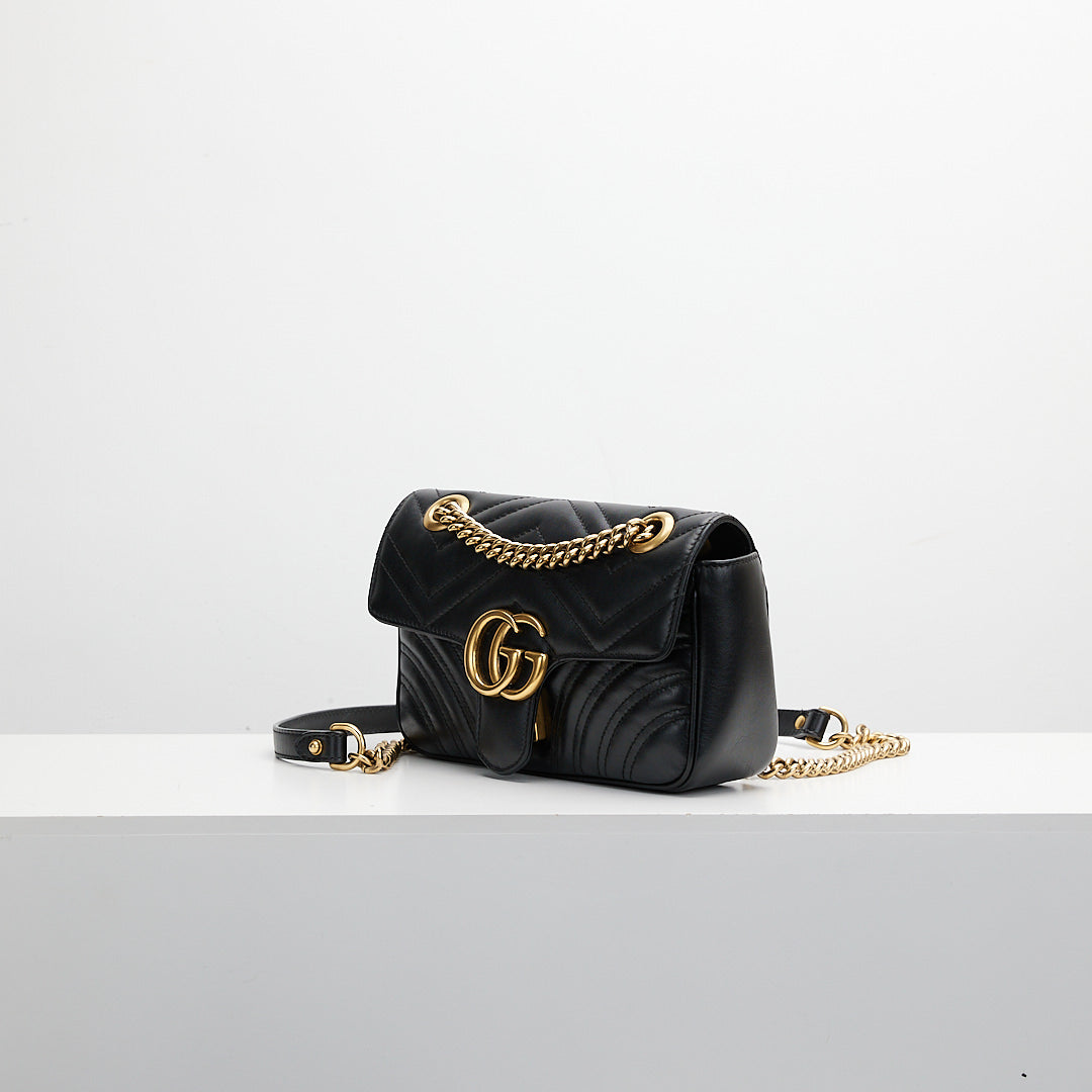 Black quilted handbag with gold chain \on a white background