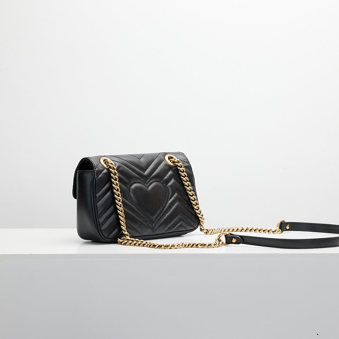 Black handbag with gold chain on a light gray background