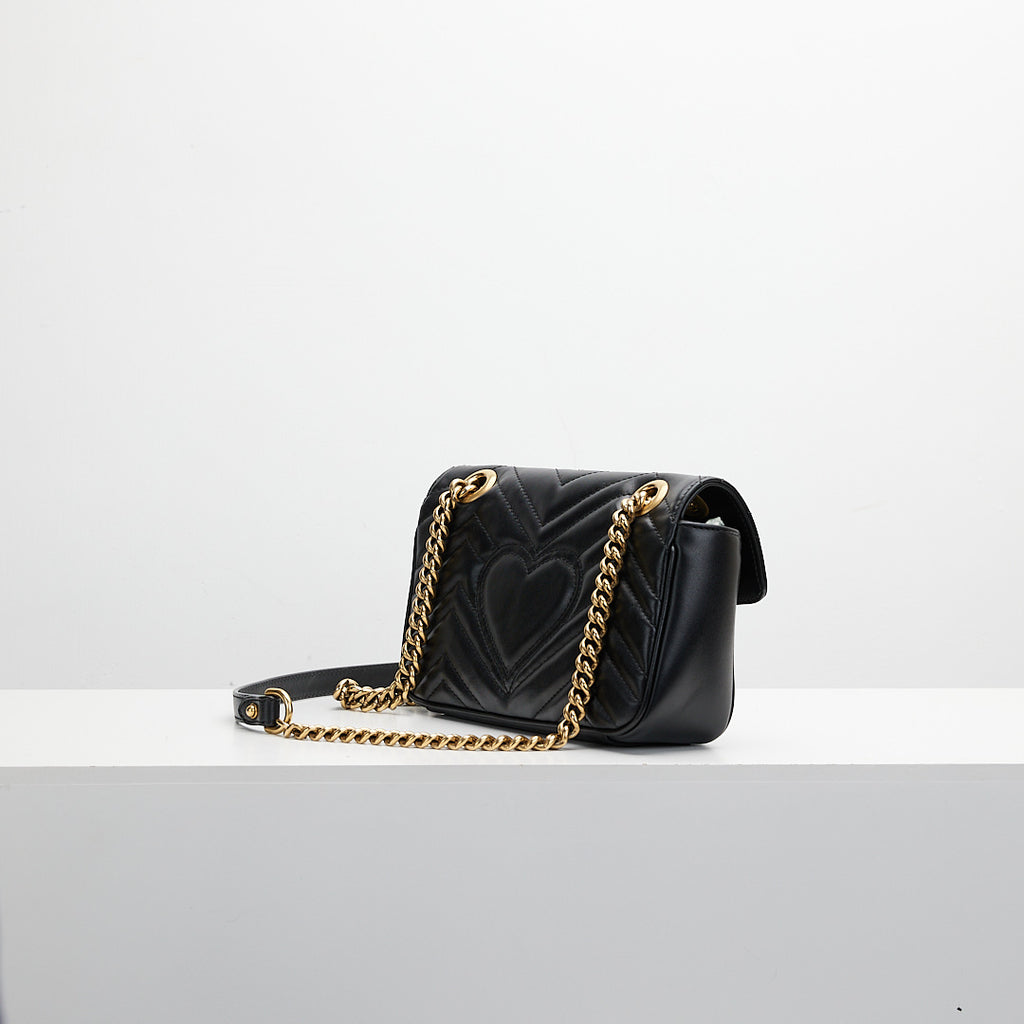 Black handbag with gold chain on a white background