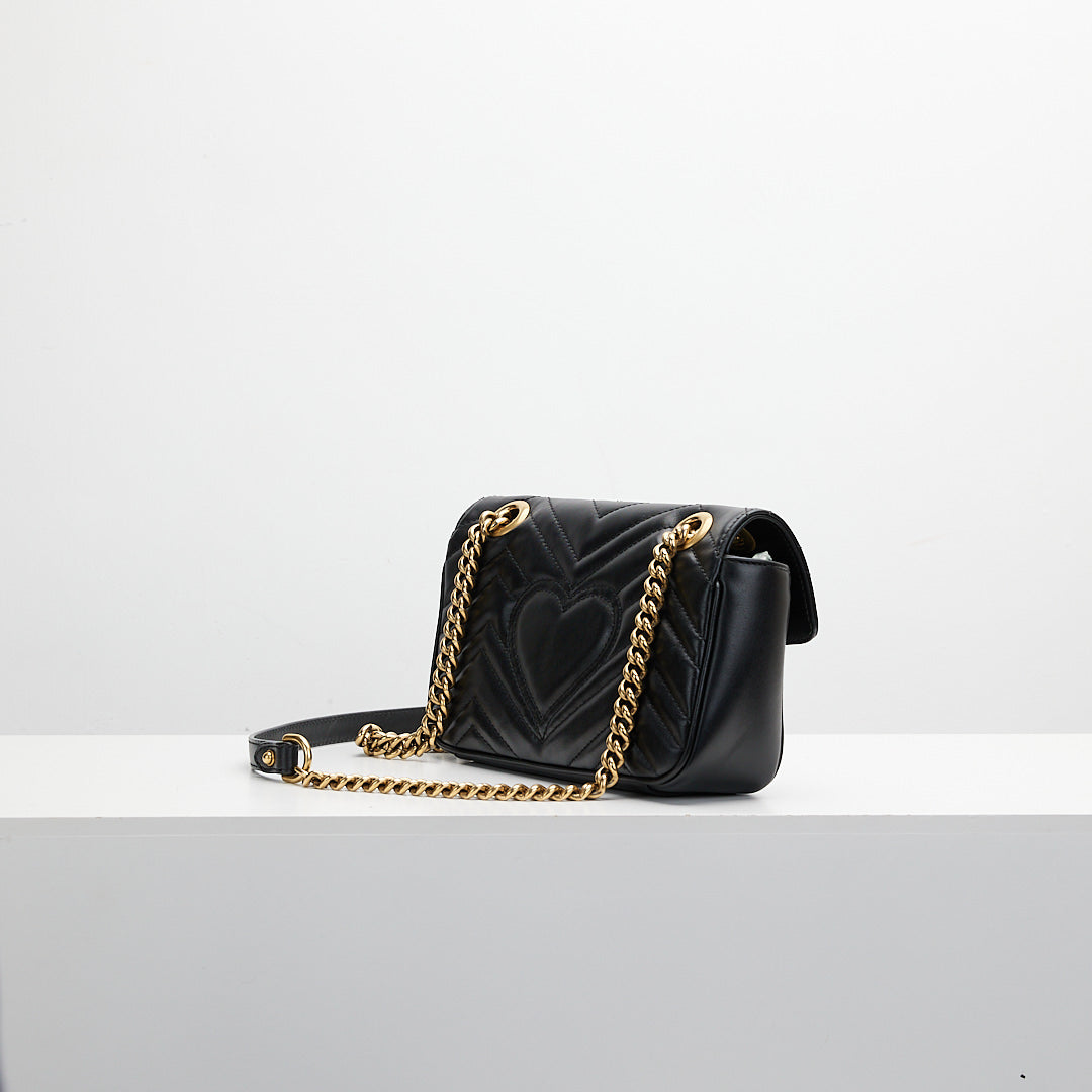 Black handbag with gold chain on a white background