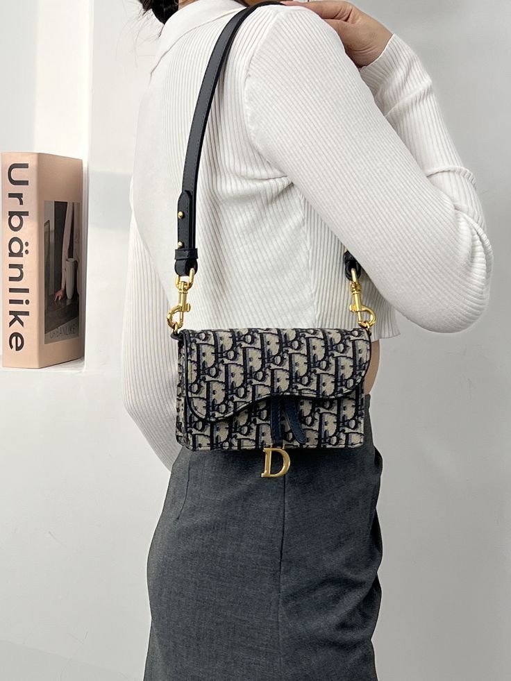Asymmetric silhouette crossbody bag in navy and beige, worn cross-body over dark blue jeans and a navy and cream sweater.