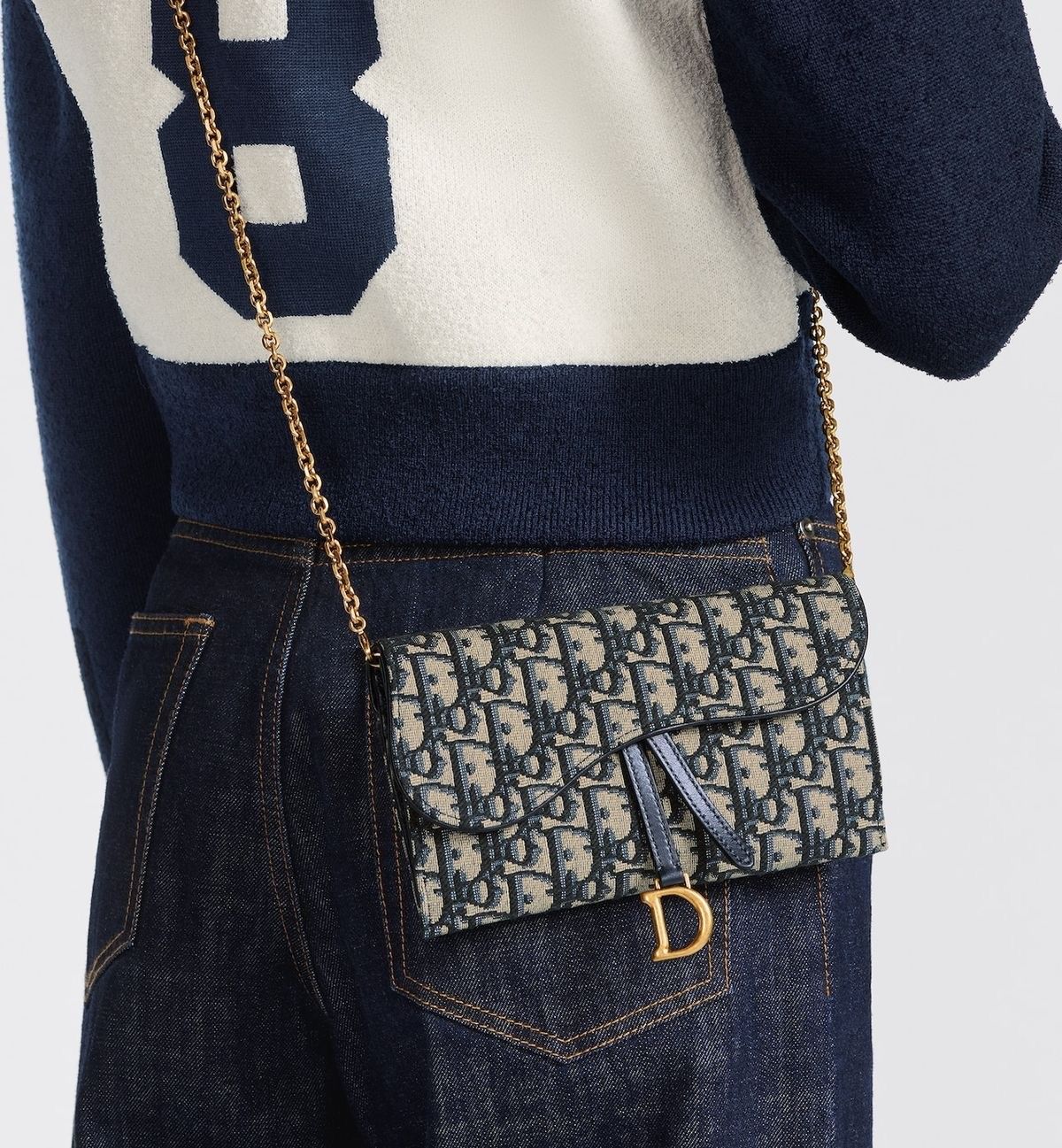 Asymmetric silhouette crossbody bag in navy and beige, worn cross-body over dark blue jeans and a navy and cream sweater.