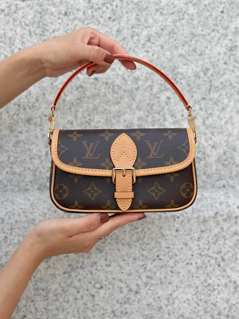 monogram handbag held by a person against a gray background