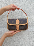 monogram handbag held by a person against a gray background
