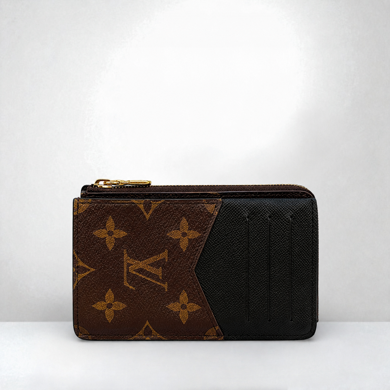 zip-around wallet in brown and black canvas, featuring gold-tone hardware, set against a plain light gray background.