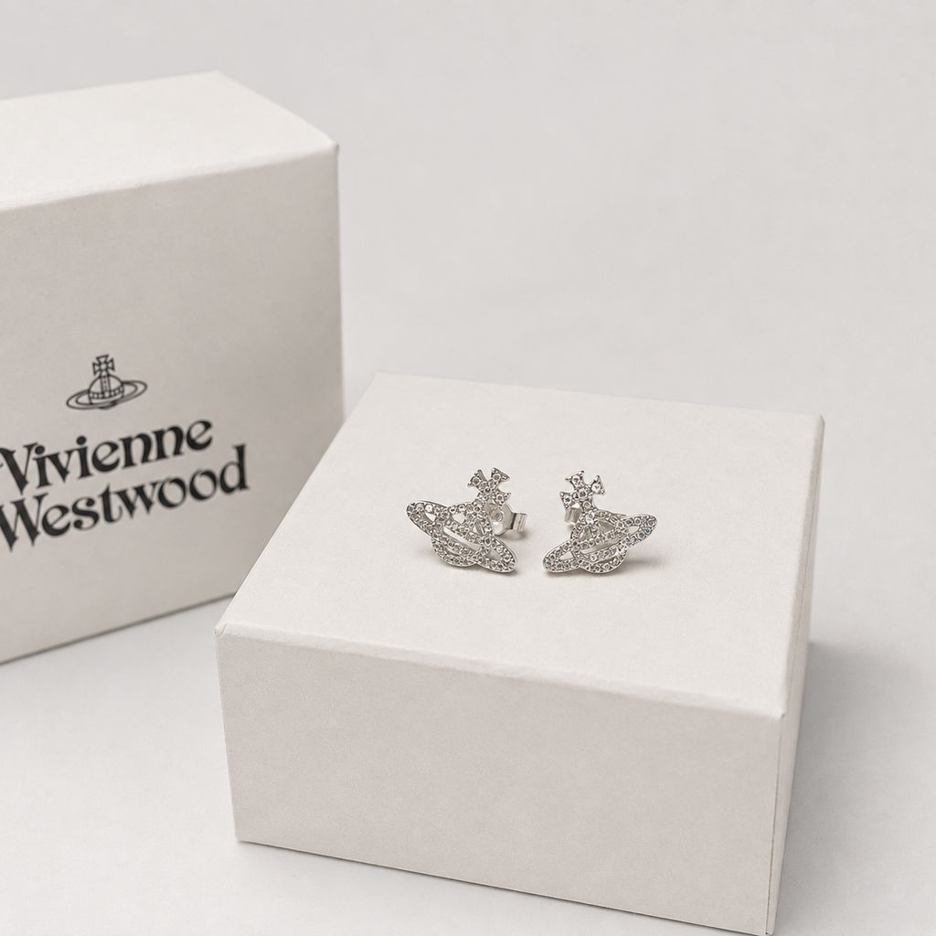 A pair of silver-tone Orb earrings displayed on a white presentation box, with the branded white box visible in the background on a clean light gray surface.