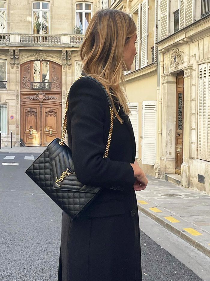 Woman holding a black quilted handbag on a city street