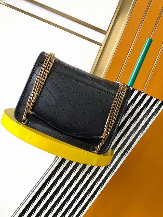 Close up of smooth black leather texture and tonal logo with gold chain detail. Sourced designer alternative handbag.