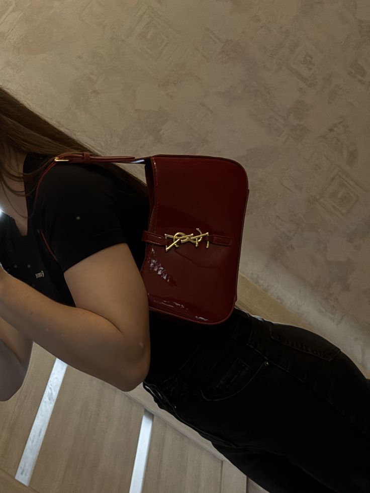 Woman styling a burgundy patent underarm bag with jeans, viral cherry red fashion aesthetic.