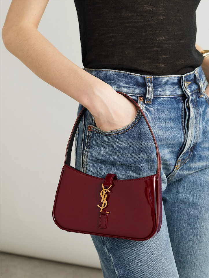 Woman styling a burgundy patent underarm bag with jeans, viral cherry red fashion aesthetic
