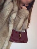 Woman styling a burgundy patent underarm bag with jeans, viral cherry red fashion aesthetic.