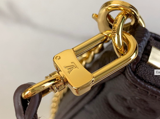 Close up of firm black grained texture and gold hardware on crossbody bag.