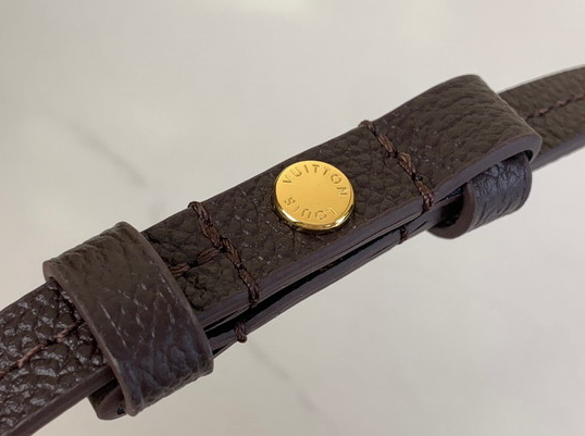 Close up of firm black grained texture and gold hardware on crossbody bag.