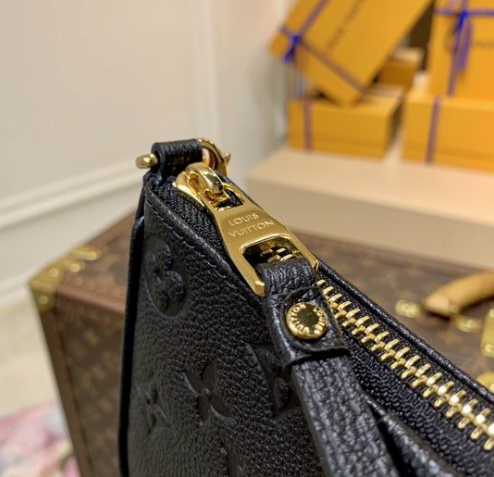 Close up of firm black grained texture and gold hardware on crossbody bag.