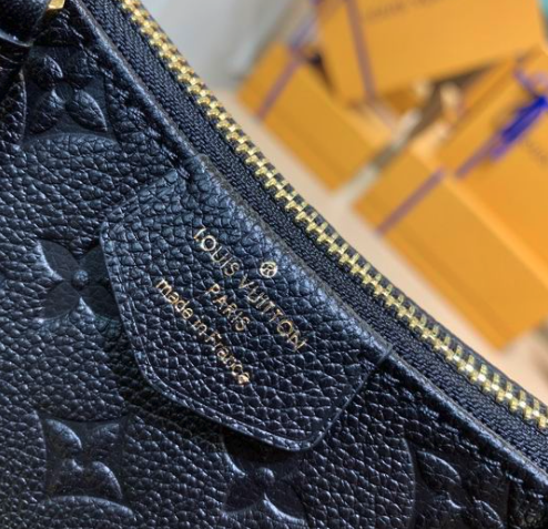 Close up of firm black grained texture and gold hardware on crossbody bag.