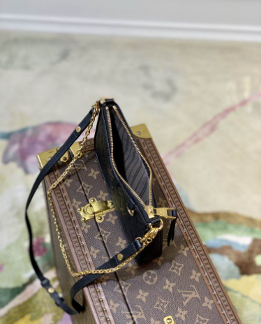Close up of firm black grained texture and gold hardware on crossbody bag.