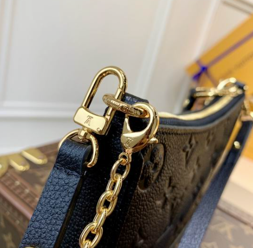 Close up of firm black grained texture and gold hardware on crossbody bag.