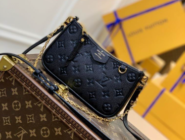 Close up of firm black grained texture and gold hardware on crossbody bag.