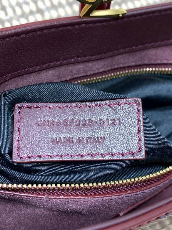 Close up of high shine burgundy patent leather texture and gold metal closure detail.