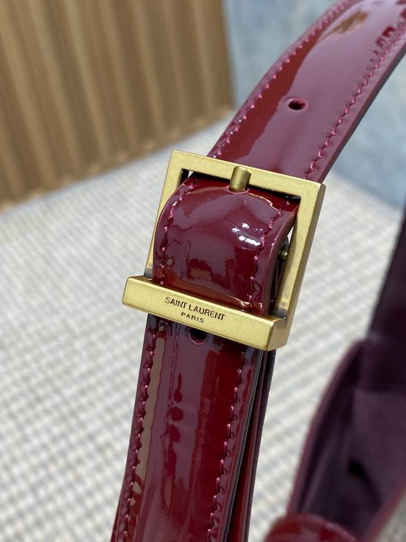 Close up of high shine burgundy patent leather texture and gold metal closure detail.