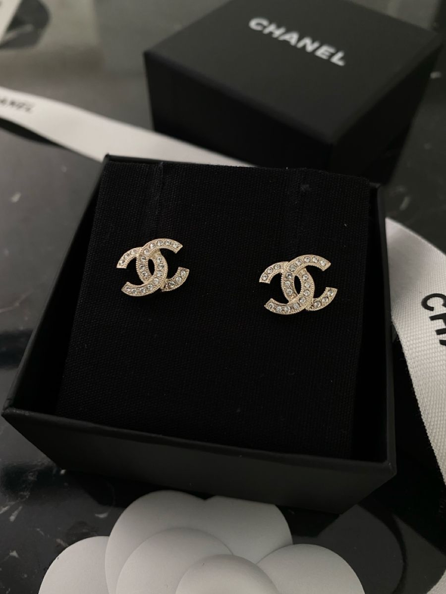 Gold interlocking crystal stud earrings with black luxury jewelry box, sourced accessible luxury accessories.