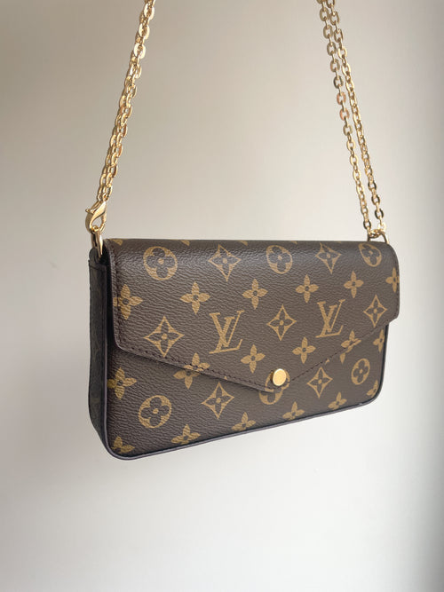 Close up of monogram envelope bag with gold chain strap, accessible luxury handbag.