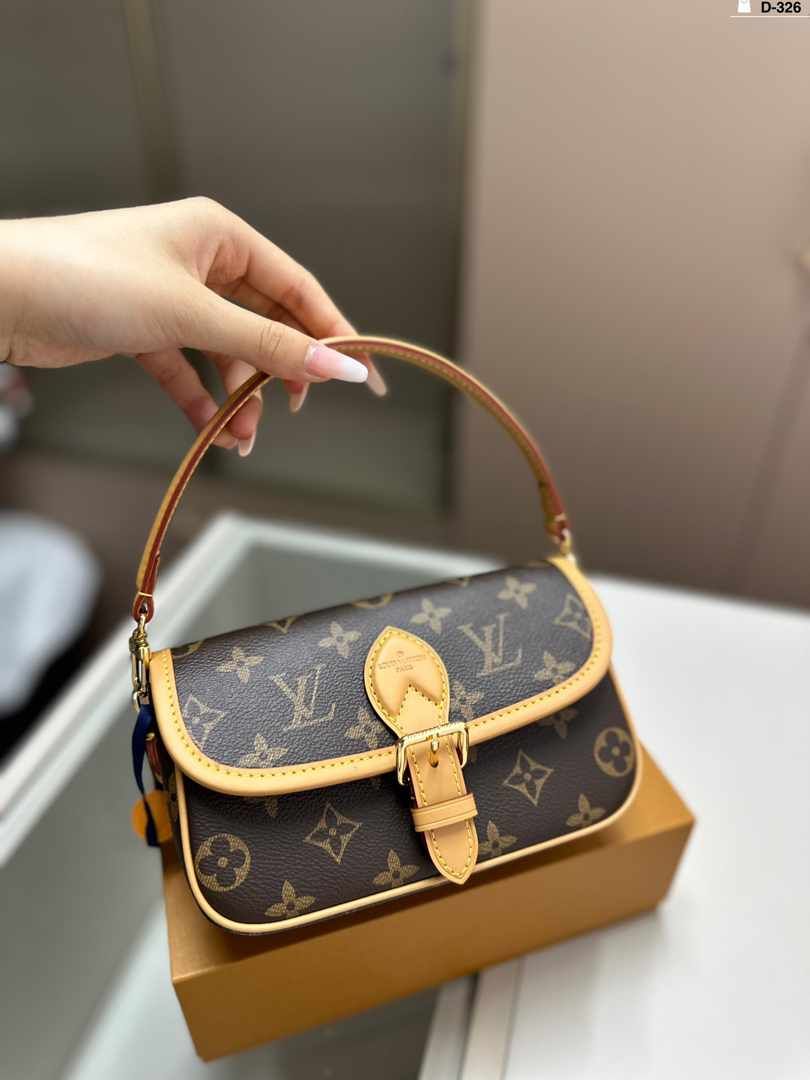 Luxury handbag with monogram pattern held by a hand on a neutral background