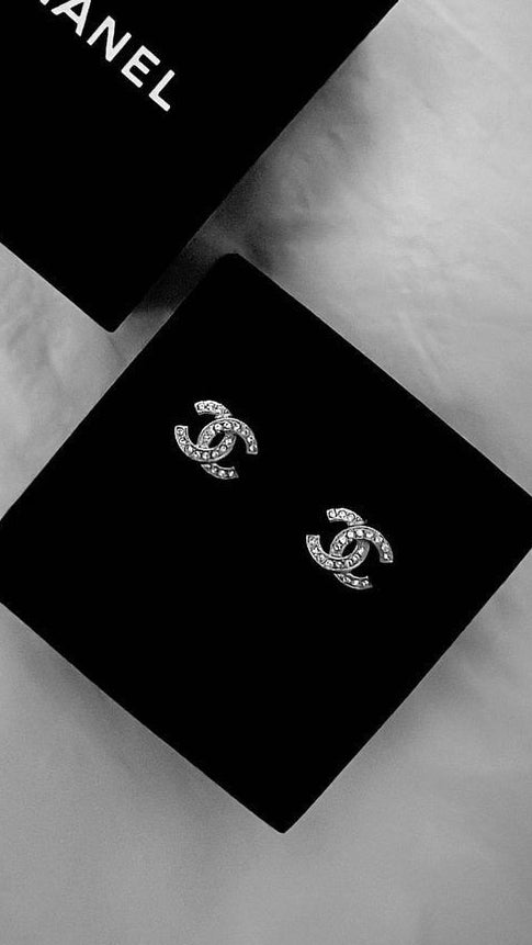 Silver interlocking crystal stud earrings with black luxury jewelry box, sourced accessible luxury accessories.