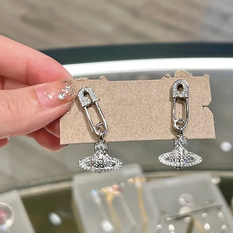 Silver earrings on a display card held by a hand with a blurred background