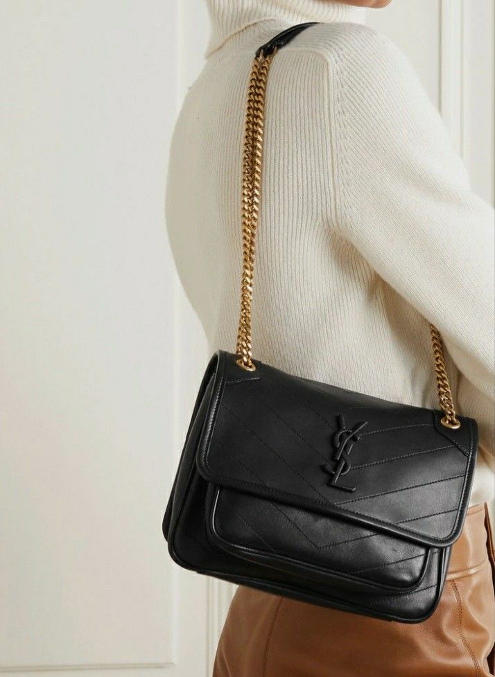 Woman styling a black slouchy flap bag with tonal logo. Cool girl aesthetic outfit with everyday luxury handbag.