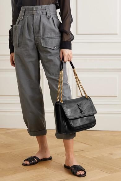Woman styling a black slouchy flap bag with tonal logo. Cool girl aesthetic outfit with everyday luxury handbag.