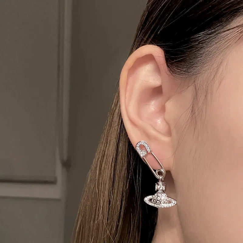 Silver earring worn by a person with a neutral background