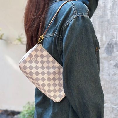 Person wearing a denim jacket with a checkered handbag over their shoulder.
